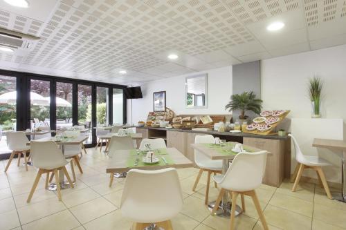 a dining room with tables and white chairs at Appart'hôtel Odalys City - Monaco Les Hauts de la Principauté in Beausoleil