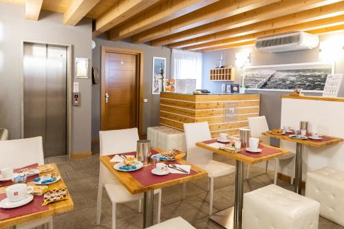 a dining room with two tables and white chairs at Hotel All'Arco in Trieste