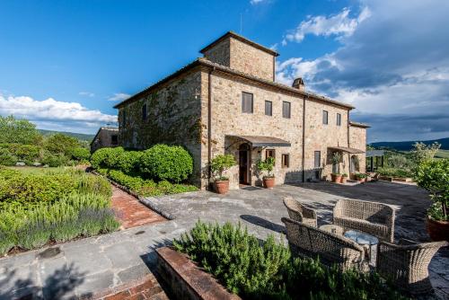 ein großes Steingebäude mit Stühlen davor in der Unterkunft Locanda Le Piazze in Castellina in Chianti