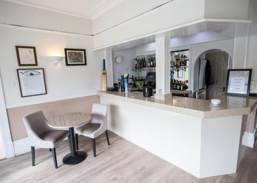 a bar with two chairs and a table in a room at Corner House Hotel Gatwick with bookable Holiday parking in Horley