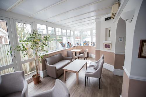a room with chairs and a table and windows at Corner House Hotel Gatwick with bookable Holiday parking in Horley