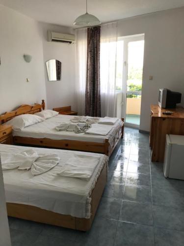 a hotel room with three beds and a television at Family Hotel Sinemoretz in Sinemorets
