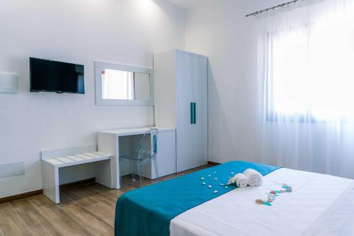 a white bedroom with a bed with a blue blanket at B&B Le Tartarughe in San Vito lo Capo
