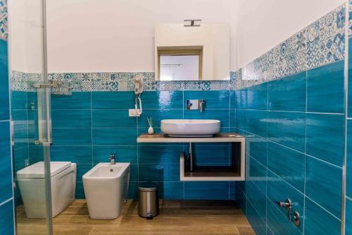 La salle de bains est pourvue de carrelage bleu, d'un lavabo et de toilettes. dans l'établissement B&B Le Tartarughe, à San Vito Lo Capo