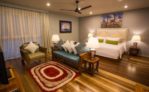 a bedroom with a bed and a couch and a chair at Sutera Sanctuary Lodges At Kinabalu Park in Kundasang