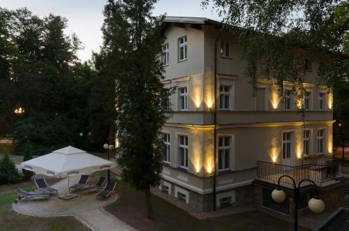 a large white building with a table and chairs at Willa Mała Pieniawa in Polanica-Zdrój