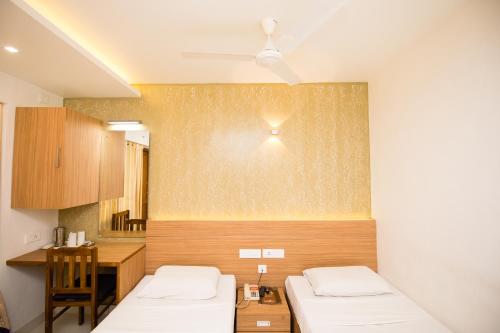 a room with two beds and a desk and a table at Hotel Kapilavasthu in Palakkad