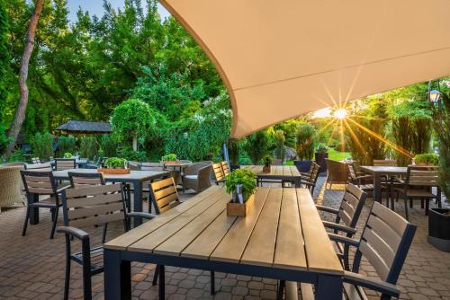 an outdoor patio with tables and chairs and the sun setting at Hotel Warszawianka in Jachranka