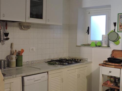 a kitchen with white cabinets and a stove top oven at La Casa nel Borgo in Tellaro