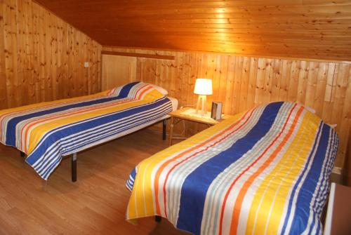 サモエンヌにあるCristalのベッド2台、テーブルの上にランプが備わる木造キャビンです。