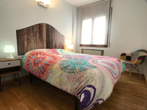 a bedroom with a bed with a colorful blanket on it at Poblat Andorrá, Encamp, con terraza, zona Grandvalira in Encamp