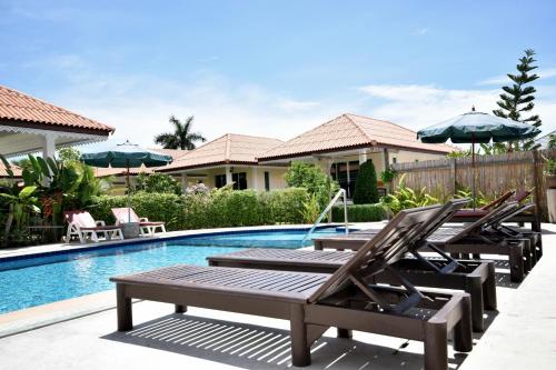 a pool with chairs and umbrellas in front of a house at Baan Opun Garden Resort in Hua Hin