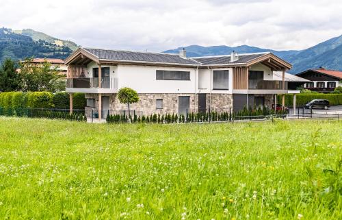 a house in a field with mountains in the background at Aurora Mountain Chalet by we rent, SUMMERCARD INCLUDED in Kaprun