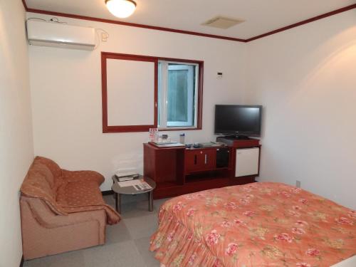a bedroom with a bed and a tv and a chair at Hotel Sango (Adult only) in Muroran