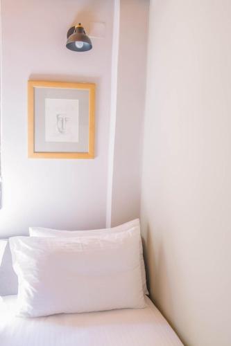 a bed with white sheets and a picture on the wall at Teatro Villa in Kato Rodini