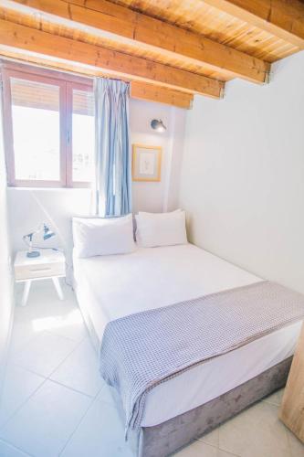 a white bedroom with a bed and a window at Teatro Villa in Kato Rodini
