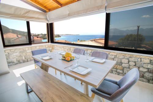 a dining room with a table and chairs and windows at Teatro Villa in Kato Rodini