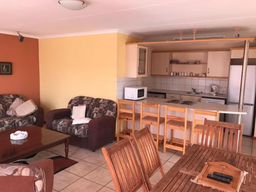 ein Wohnzimmer mit einem Sofa, einem Tisch und einer Küche in der Unterkunft Marina Sands in Jeffreys Bay