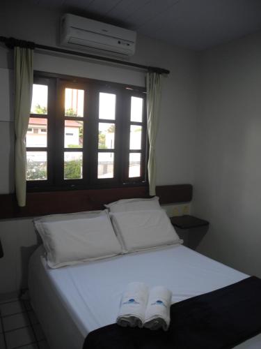 a bed with two white pillows and a window at Praia Apart Hotel in Natal