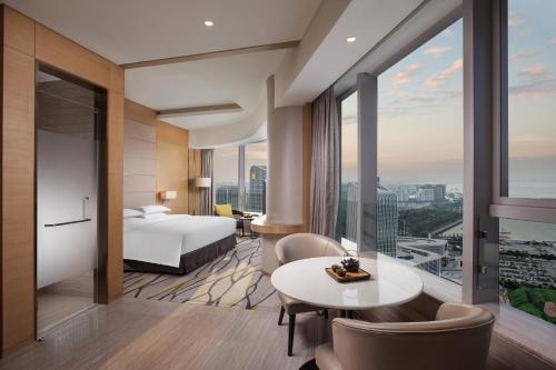 a hotel room with a bed and a table and chairs at Fliport Wutong Hotel-Free Welcome Fruit & Near Exhibition Center in Xiamen