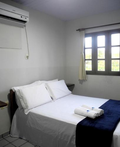 a bedroom with a white bed with two towels on it at Praia Apart Hotel in Natal