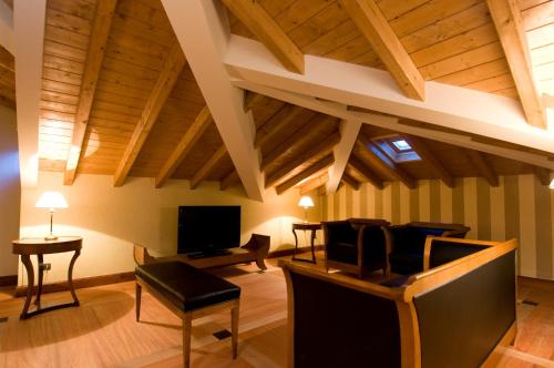 a living room with wooden ceilings and a tv at Hotel Villa Del Sogno in Gardone Riviera
