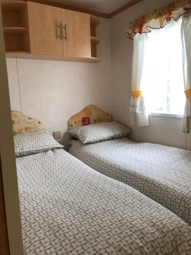 two beds in a small room with a window at 57 Glenfinart Caravan Park in Ardentinny