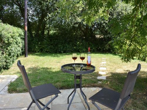 a table with two glasses of wine and two chairs at Nutley Farm in Winfrith Newburgh