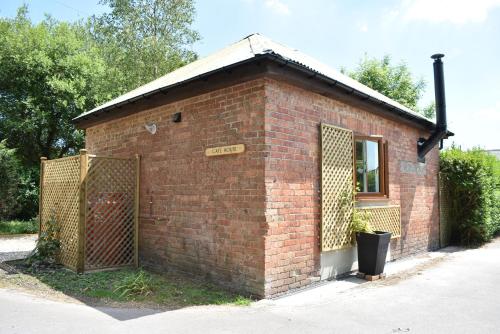 a brick building with a gate on the side of it at Nutley Farm in Winfrith Newburgh