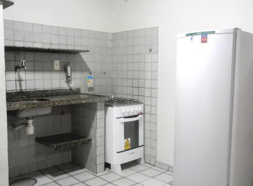 a kitchen with a stove and a sink and a refrigerator at Praia Apart Hotel in Natal