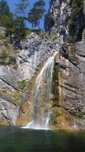 a waterfall on the side of a mountain next to a lake at Alpen Natur Camp in Gröbming