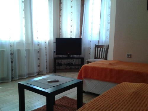 Habitación con 2 camas, TV y mesa. en Apartment Domino, en Belogradchik