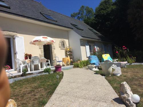 a house with chairs and an umbrella in the yard at aux 2 oies in Plouider