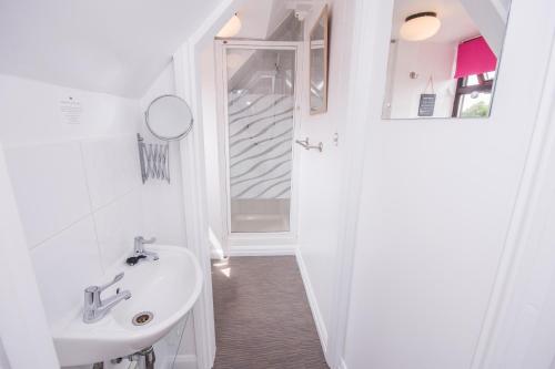 a white bathroom with a sink and a mirror at The Mariners Guest House in Poole
