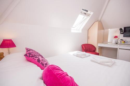 a bedroom with a white bed with pink pillows at The Mariners Guest House in Poole