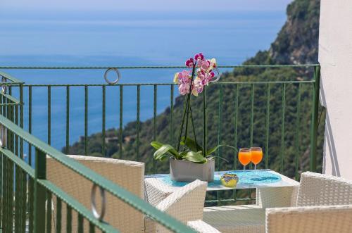 a table with a flower and a glass of orange juice on a balcony at Amalfi Dream Charming House in Scala