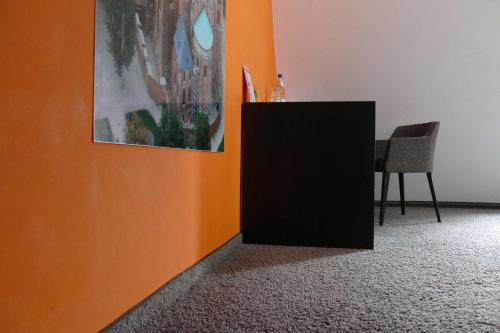an orange wall with a black cabinet next to a table at Maximilian in Speyer
