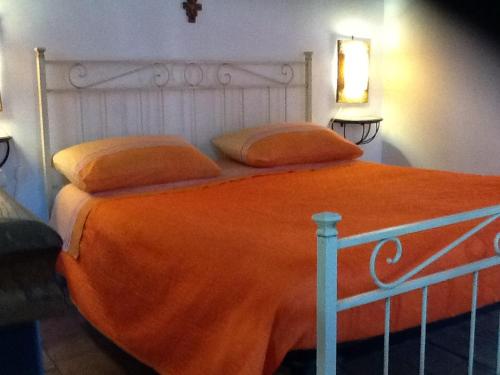 a bed with an orange blanket and pillows on it at Rifugio di campagna in Vitorchiano