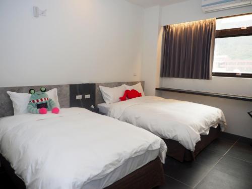 a bedroom with two beds with white sheets and a window at GOD’S Queen Esther in Nangan