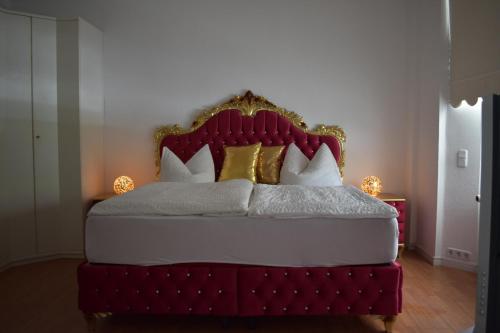 ヴィルヘルムスハーフェンにあるHotel Ammerland Appartementsのベッドルーム1室(赤と金のヘッドボード付きのベッド1台付)