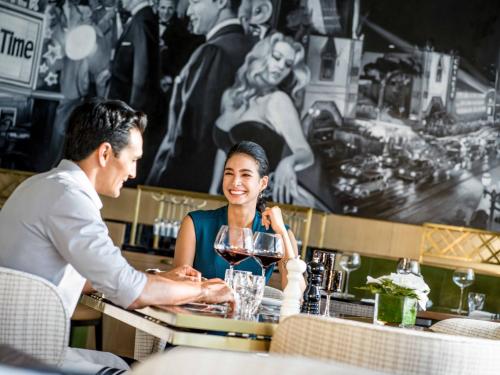 a man and woman sitting at a bar drinking wine at InterContinental Hanoi Landmark72 by IHG in Hanoi