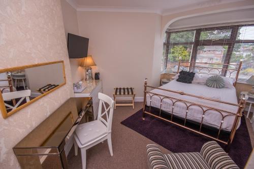 a bedroom with a bed and a desk and a mirror at The Mariners Guest House in Poole
