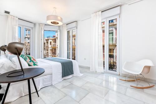 1 dormitorio blanco con 1 cama, mesa y sillas en Apartamento Calle Martínez - Larios, en Málaga