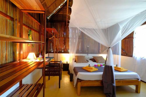 a bedroom with two beds and a desk and a table at Coco Komba Lodge in Nosy Komba