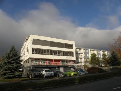 a white building with cars parked in a parking lot at Penzión Inštitút in Košice