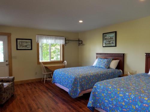 a bedroom with two beds and a chair and a window at Grand View Resort in Weirs Beach