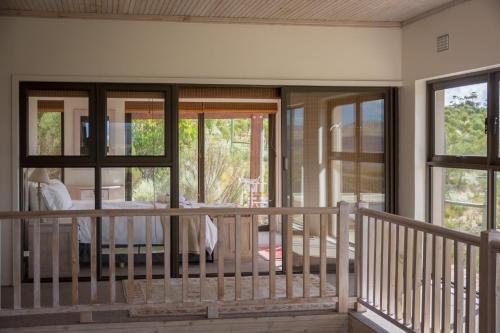 a balcony with glass doors and a bed on a porch at Barton Luxury Villas in Botrivier