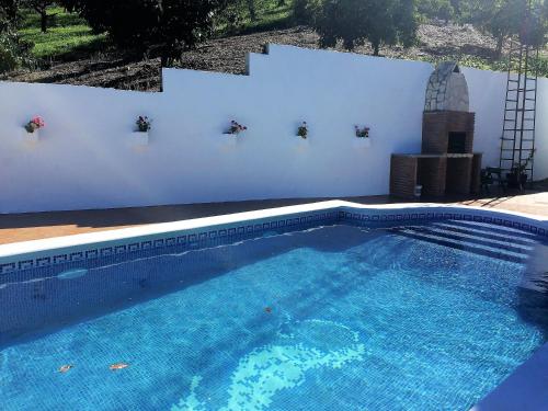 a large blue swimming pool with a white wall at Casa las Torres B&B in Iznate
