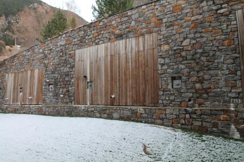 due porte in legno su un muro di pietra con neve di Salze, Canillo, Zona Grandvalira a Canillo