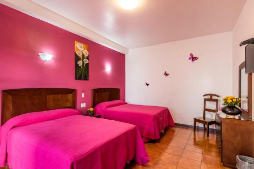 two beds in a room with pink sheets at Hotel del Marquesado in Oaxaca City